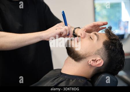 Der professionelle Groomer trimmt Gesichtsbehaarung mit präziser Klingentechnik Stockfoto
