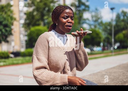 Die afroamerikanische Frau ist verzweifelt, wenn sie ihr Smartphone für Online-Nachrichten nutzt. Stockfoto