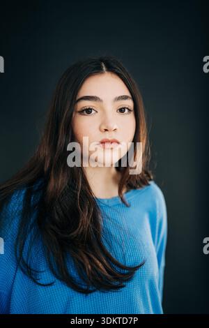 Junge Frau posiert mit neutralem Ausdruck im Studio Stockfoto