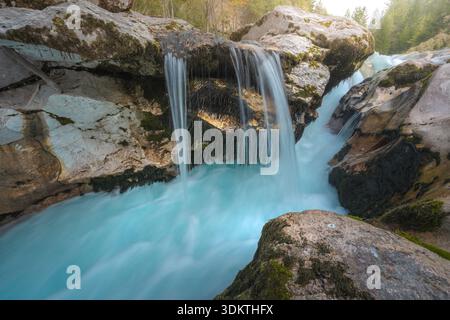 Blick auf türkisfarbenes Wasser, das über moosbedeckte Felsen stürzt und eine ruhige und malerische Szene der Schönheit der Natur schafft, Soča, Tolmin, Slowenien. Stockfoto