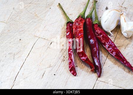 Vier rote Paprika sind auf einem hölzernen Schneidebrett. Die Paprika sind getrocknet und scheinen bereit für die Verwendung in einer Schale zu sein. Das Schneidebrett besteht aus Holz A Stockfoto