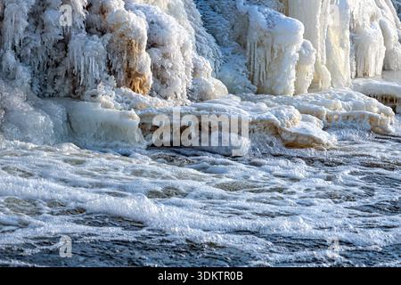 Gefrorenes Wasser fließt über Felsen und bildet im Winter Eis in einem Fluss Stockfoto