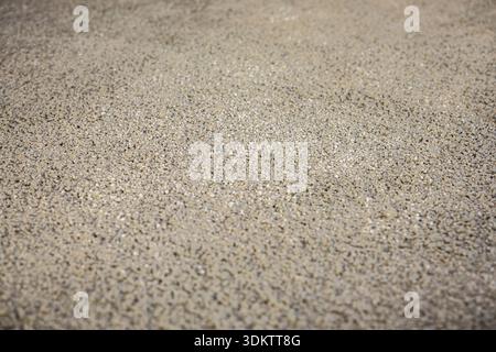 Detaillierte Ansicht einer strukturierten Oberfläche aus kleinen, gleichmäßig verteilten Kieselsteinen, die wahrscheinlich Teil eines Bodenbelags oder einer Fußbodenheizung sind. Stockfoto