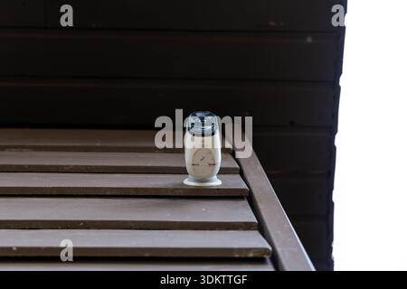 Ein weißer, zylindrischer WLAN-Router mit schwarzer Oberseite sitzt auf horizontalen Holzlatten. Der Hintergrund zeigt eine dunkle Holzwand in einem offenen Bereich eines Pri Stockfoto