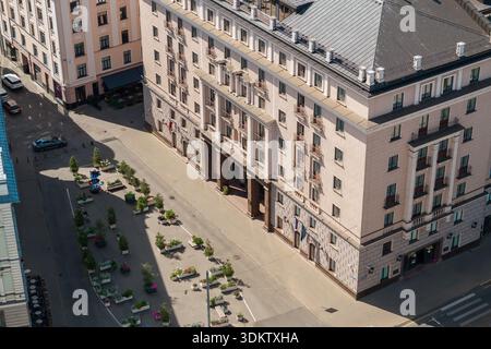 Blick aus der Vogelperspektive auf eine Straße in Riga, Lettland, mit einem mehrstöckigen Gebäude mit einer hellen Fassade, Balkonen, schrägem Dach und dekorativen Säulen am e Stockfoto