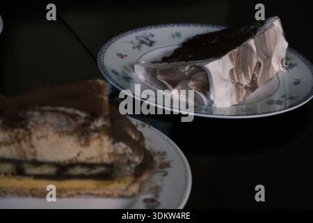 Nahaufnahme mit köstlichem Tiramisu-Kuchen, serviert auf einem Teller mit Blumenmuster in einem stimmungsvollen Café in Yokohama, Japan Stockfoto