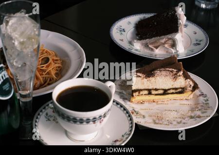 Japanisches Café mit Spaghetti, Schokoladenkuchen, Tiramisu und Kaffee auf einem dunklen Tisch Stockfoto