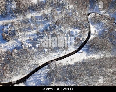 Blick von oben auf die gekrümmte Straße, umgeben von weißen schneebedeckten Bäumen in Nagano im Winter Stockfoto