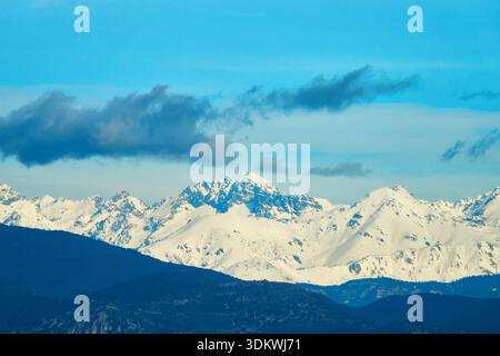 Schneebedeckte Bergkette unter klarem blauen Himmel mit Wolken und rollendem Vorder Stockfoto