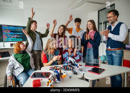 Ein vielseitiges High School Team feiert Teamarbeit während eines Robotik-Projekts. Stockfoto