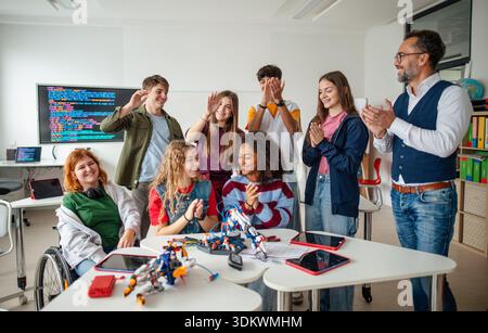 Ein vielseitiges High School Team feiert Teamarbeit während eines Robotik-Projekts. Stockfoto