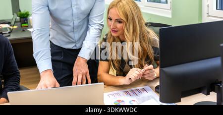 Banner mit Geschäftskollegen, die in einem modernen Coworking-Büro an einem Laptop arbeiten Stockfoto