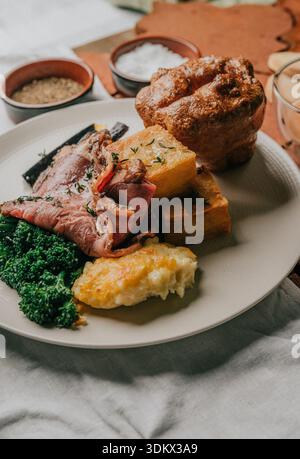 Ein Teller mit Speisen mit einer Vielzahl von Fleisch und Gemüse. Die Platte wird auf einen Tisch gestellt, unter dem ein Tuch steht Stockfoto