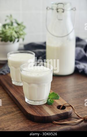 Zwei Gläser traditionelles türkisches Getränk Ayran, Kefir oder Buttermilch, hausgemachter einfacher Joghurt aus nächster Nähe auf Holztisch Stockfoto