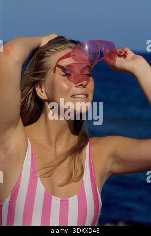 Hübsches blondes Haar junge Frau schöne blondes Haar sehr hübsches junges Gesicht Nahaufnahme Kamera auf ihre Nase eine moderne rosa Sonnenbrille mit rosa Stockfoto