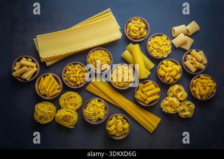 Komposition mit verschiedenen leckeren rohen Nudeln - italienische Nudeltapete, verschiedene Arten und Formen des Pasta-Layouts Stockfoto
