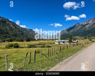 Malerische ländliche Landschaft entlang der Carretera Austral in Patagonien, Chile, mit einem Abschnitt einer unbefestigten Feldstraße, die neben einem einfachen Holzzaun verläuft. Stockfoto