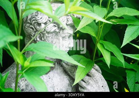 Eine Gartenstatue einer klassischen Figur, umgeben von üppigem Grün. Stockfoto