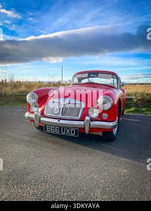 Ein klassischer roter MG A MGA-Sportwagen, der neben einer landschaftlich schönen Grünfläche parkt. Stockfoto