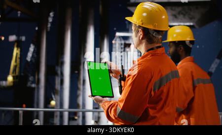 Vertikaler grüner Bildschirm mit Mitarbeitern, die die Ölbohrungen auf Offshore-Plattformen überwachen und Technologien zur Gewinnung von Erdgas und Erdöl aus Meereshabitaten einsetzen. Ölindustrie. Stockfoto