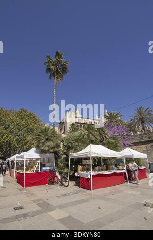 PALMA, MALLORCA, SPANIEN - 9. APRIL 2019: Händlerhütten mit Kunsthandwerk und Schloss Almudaina im Hintergrund an einem sonnigen Tag am 9. April 2019 in Palma Stockfoto