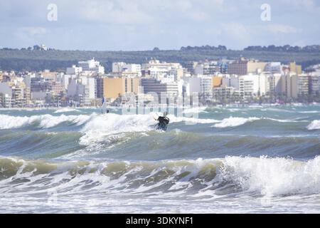 CAN PASTILLA, MALLORCA, SPANIEN - 6. APRIL 2019: Surfer in die grünen Wellen spielen an einem windigen, sonnigen Tag am 6. April 2019 in Can Pastilla, Mallorca, Sp Stockfoto