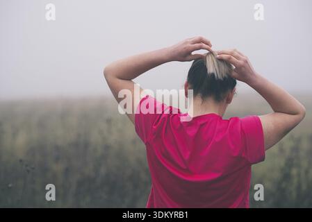 Junge Frau zur Festsetzung Haar draußen vor der Ausführung Stockfoto