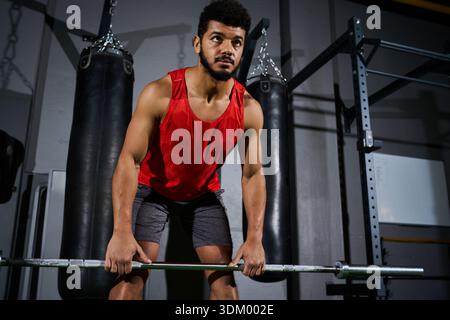 Ein engagierter junger Mann mit Bart führt im Fitnessstudio ein Gewichtheben durch. Stockfoto