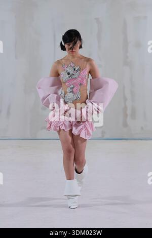 Berlin, Deutschland, 2. Februar 2026. Ein Model läuft auf einer minimalistischen weißen Laufstege, die während der Kasia Kucharska Herbst/Winter 2026 (AW26)-Präsentation einen avantgardistischen Look zeigt. Das Outfit besteht aus einem transparenten, fleischfarbenen Oberteil, das mit einer glitzernden grafischen Illustration eines weißen Zeichentrickkätzchens mit rosa Schleife und einem pinken Minirock mit Rüschen verziert ist. Der Look ist mit voluminösen, abnehmbaren, extragroßen, rosa Ärmeleinsätzen tief an den Armen getragen und von spitzen weißen Stiefeln mit Bündchen befestigt. Der raue Studiohintergrund unterstreicht die verspielte, moderne Silhouette. Quelle: Felix Wolf/Alamy Live News Stockfoto