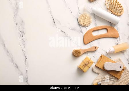 Komposition mit hölzernem guasha-Körpermassagewerkzeug und Seifenstäbchen auf Marmorhintergrund Stockfoto