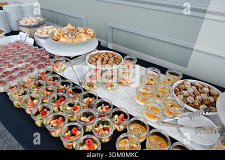Elegantes Dessertbuffet mit verschiedenen Mini-Süßigkeiten, Obstbechern und Gebäck für Catering-Events oder Hotelfrühstück Stockfoto