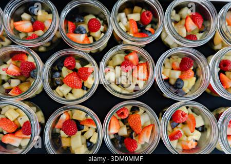 Eleganter Obstsalat, serviert in kleinen Glasgläsern, farbenfrohe frische Beeren und gewürfelte Früchte, die ordentlich für das Catering-Buffet oder das Hotelfrühstück arrangiert werden Stockfoto