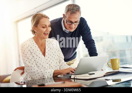 Lächeln, Paare und Lesen mit Laptop zu Hause für Recherche, Balance und finanzielle Bezahlung. Reife Menschen, pc und Tippen für Online-Banking, Haushalt Stockfoto