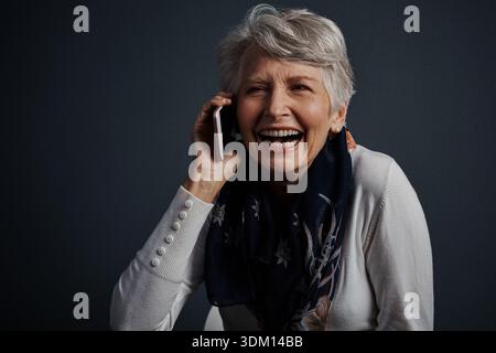 Studio, Telefonanruf und Seniorinnen lachen mit Kontakt für Kommunikation, Nachrichten oder lustige Geschichten. Mobil, älterer Mensch und Sprechen für Witze, Verbindung Stockfoto