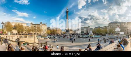 LONDON - 11. APRIL 2022: Touristen zu Fuß auf dem Trafalgar Square, London, England, Großbritannien. Der Platz ist seit dem 1200s ein bedeutendes Wahrzeichen Stockfoto