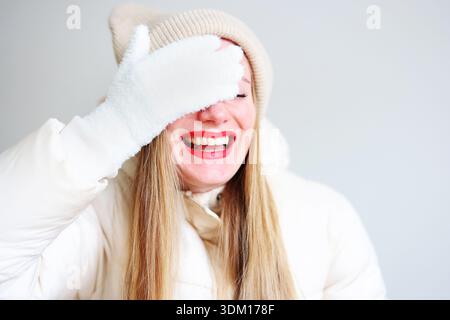Fröhliches Winterporträt einer lächelnden Frau in warmer Kleidung mit rotem Lippenstift Stockfoto