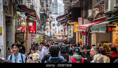MACAU CHINA - 27. DEZEMBER 2025: Belebte Gasse mit vielen Menschen, die Souvenirläden und Bäckereien in der Altstadt von Macau besuchen Reisetourismus h Stockfoto