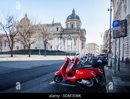 Rote Vespas parkten in einer Schlange vor der Kirche Basillica an der Rom Straße in Italien Stockfoto