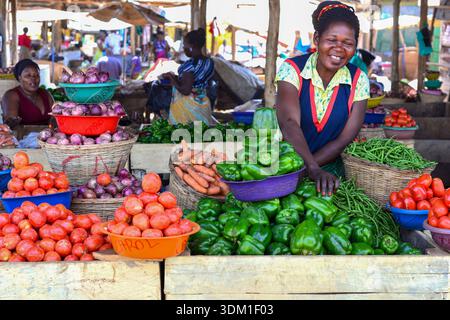 Eine fröhliche Frau verkauft frische Produkte auf dem Kalerwe Market in Kampala, Uganda, und bringt Farbe, Leben und lokalen Geschmack auf einen der geschäftigsten Märkte der Stadt. P Stockfoto