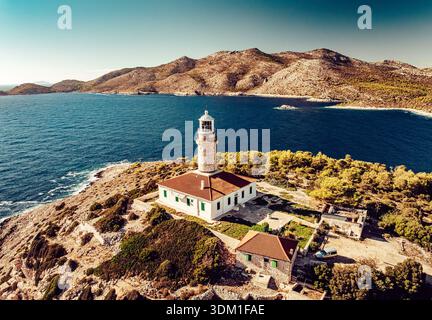 Blick aus der Vogelperspektive auf einen Leuchtturm mit einem roten Dach, der hoch auf einem felsigen Felsvorsprung steht, umgeben vom tiefblauen Meer und sonnengeküssten Hügeln, Lastovo, Dubrovni Stockfoto