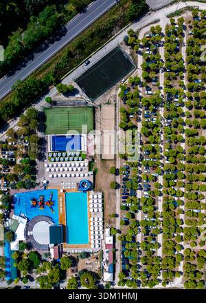 Blick aus der Vogelperspektive auf glitzernde türkisfarbene Pools im Kontrast zu den tiefgrünen Sportfeldern und der dichten Baumbedeckung, Torre di Palme, Marken, Italien. Stockfoto