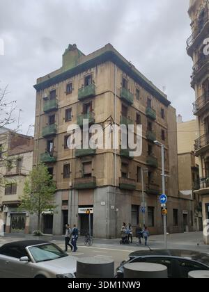 Altes Wohngebäude in der Stadt Barcelona. Er biegt eine Ecke ab und es sind Leute auf der Straße Stockfoto