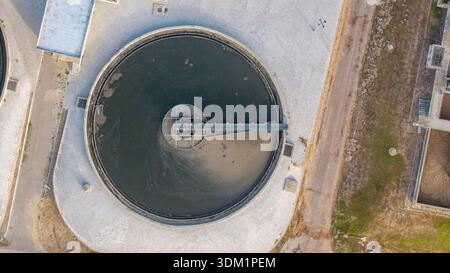 Aus der Vogelperspektive einer kreisrunden Wasseraufbereitungsanlage mit gedämpftem grauem Wasser im Kontrast zum umgebenden Beton und gerösteten Vegetation, Kraaifo Stockfoto