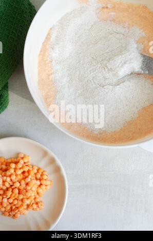 Linsen mit Vollkornmehl in einer weißen Schüssel. Gesundes veganes Backkonzept mit natürlichen Texturen und minimalem Hintergrund, gesunde Ernährung Themen. Oben Stockfoto