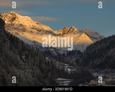 Die schneebedeckten Berge aus der Vogelperspektive erfreuen sich im warmen Glanz der untergehenden Sonne, im Kontrast zu den tiefen Schatten des Tals, Brusio, Bündner und Switz Stockfoto