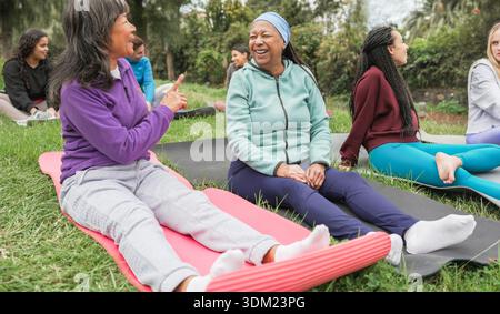 Multirassische Frauen, die Yoga-Übungen im Freien im Stadtpark machen - gesundes Lebensstil und Sportkonzept - Hauptfokus auf afrikanisches Seniorengesicht Stockfoto