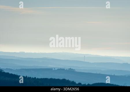 Stimmungsvolle Landschaft mit sanften Hügeln, die unter hellem Himmel allmählich in Nebel versinken. Stockfoto