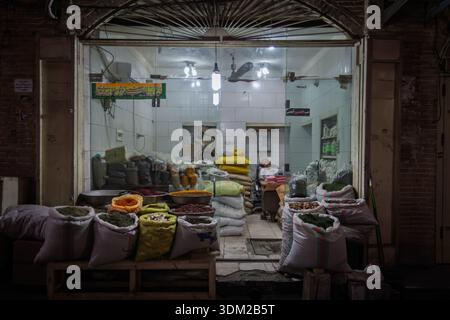ISFAHAN, IRAN - 8. AUGUST 2016: Lebensmittelhändler sitzt in einem Basar-Shop mit Säcken mit Kräutern, Bohnen, Nüssen, Gewürzen, iranischen Grundnahrungsmittel und Speisensuppe Stockfoto