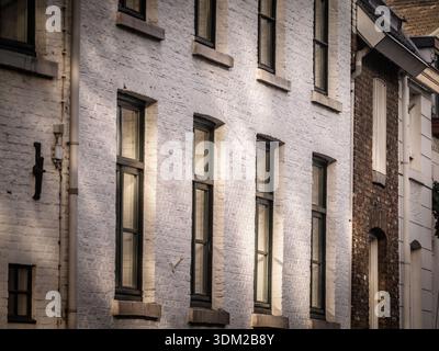 Blick auf die Wohnfassaden in Maastricht, Niederlande, mit weißer Backsteinarchitektur und renovierten Fenstern im historischen Stadtzentrum Stockfoto