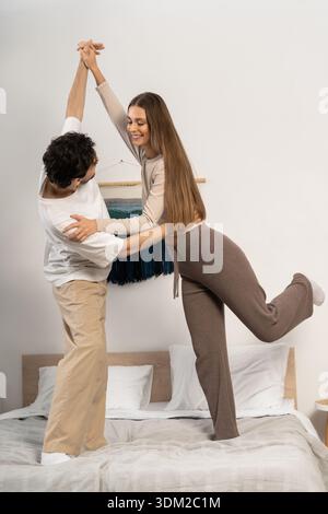 Ein junges Paar genießt eine schöne Zeit zusammen und tanzt spielerisch in seinem stilvollen Zuhause. Stockfoto